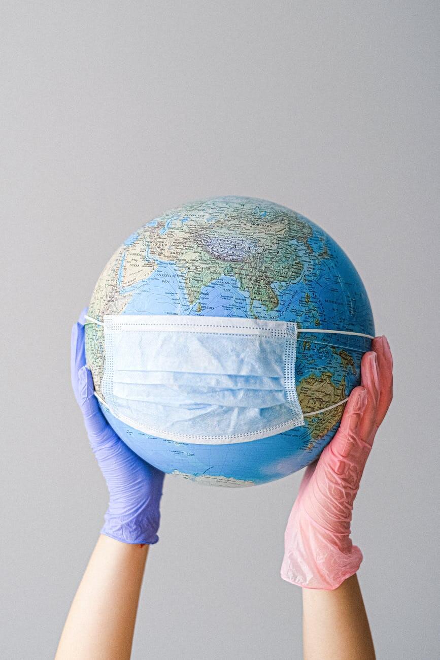4 Tips For Developing A Successful Affiliate Marketing Strategy - hands with latex gloves holding a globe with a face mask